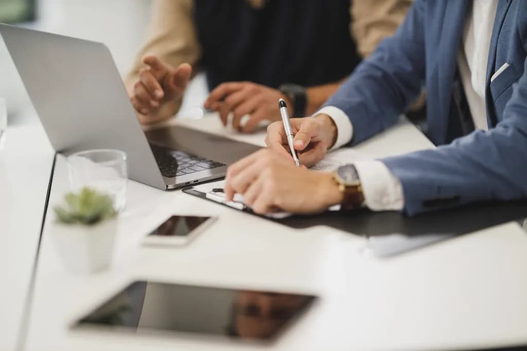 Professionals reviewing and signing client documents at a laptop